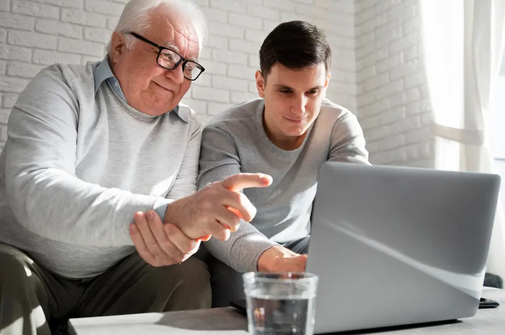 Accompagnement informatique individuel et bienveillant d'une personne âgée sur un ordinateur portable par un conseiller de l'association.